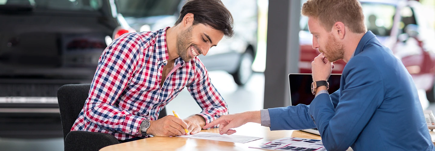 salesman pointing at the contract to the man to sign