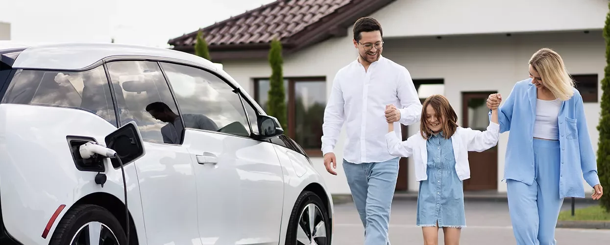 A famliy holding hands walking over to there EV charging in there driveway