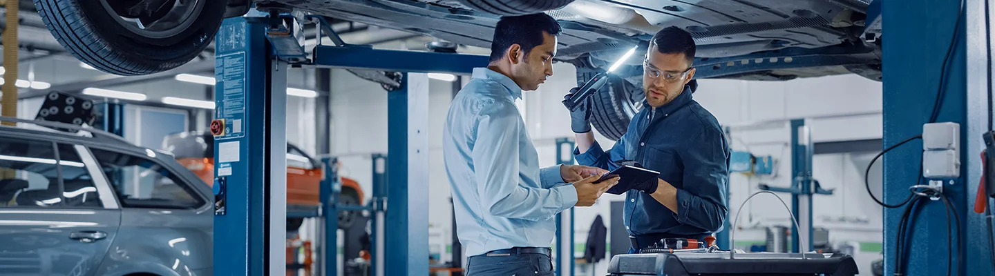 Two service techs working on a car