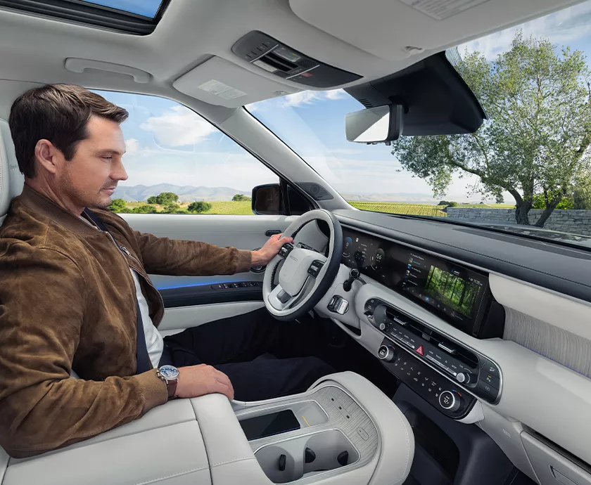 A man sitting in a 2027 Hyundai Palisade looking at the dashboard and tech