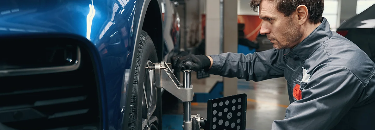 auto mechanic worrking tire allignment on a car in service bay