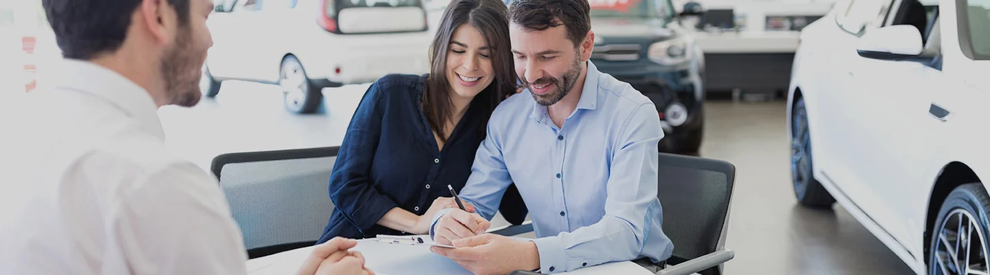 a couple speaking with car salesperson in dealership