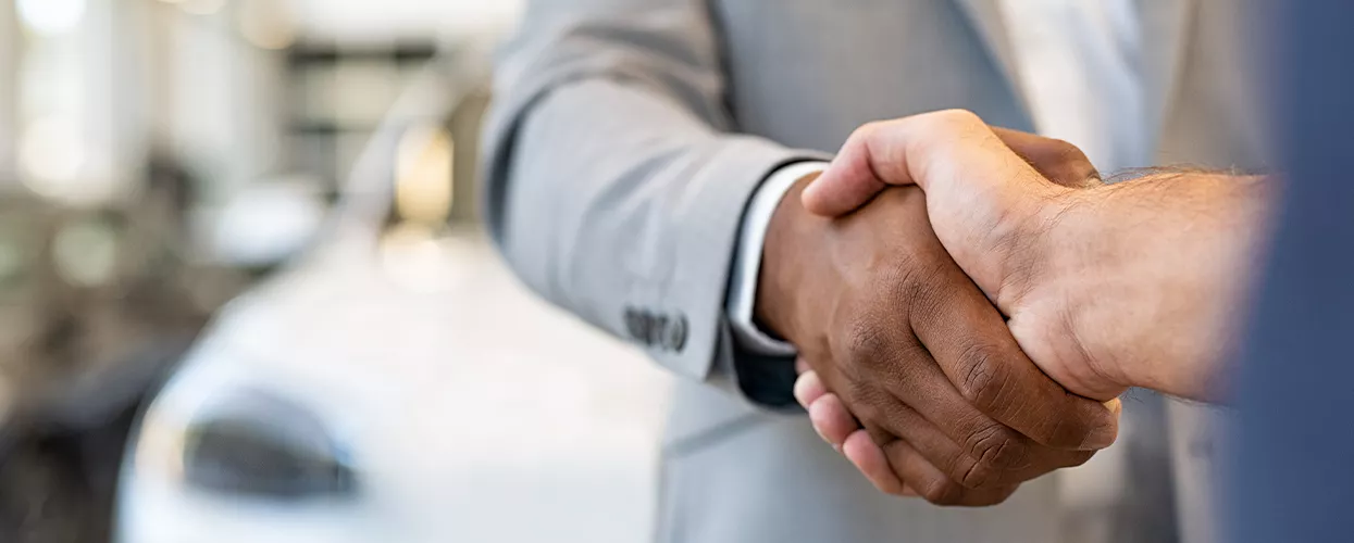 Two people shaking hands in a car dealership