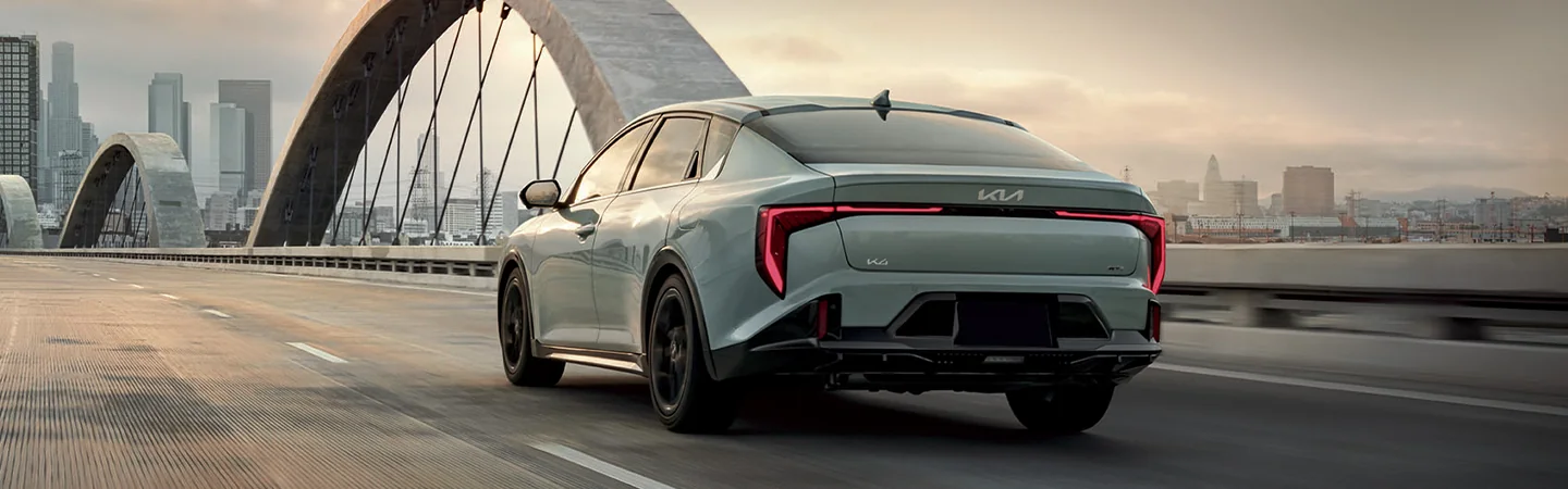Back view of a 2025 Kia K4 driving over a bridg into the city