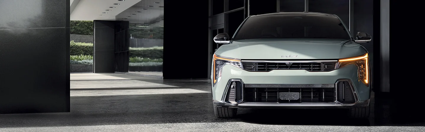 Front view of a parked 2025 Kia K4 next to a building
