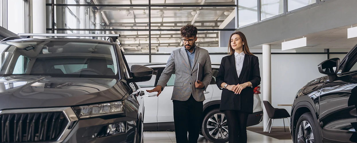 A man and woman are standing next to a car in a showroom, emphasizing the car's style and the showroom's ambiance.