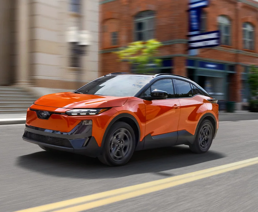 Front side view of a orange 2026 Subaru Uncharted driving in a city