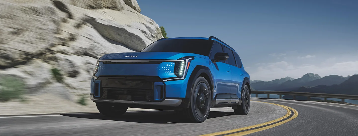 front view of a blue 2026 Kia EV9 on a mountian turn