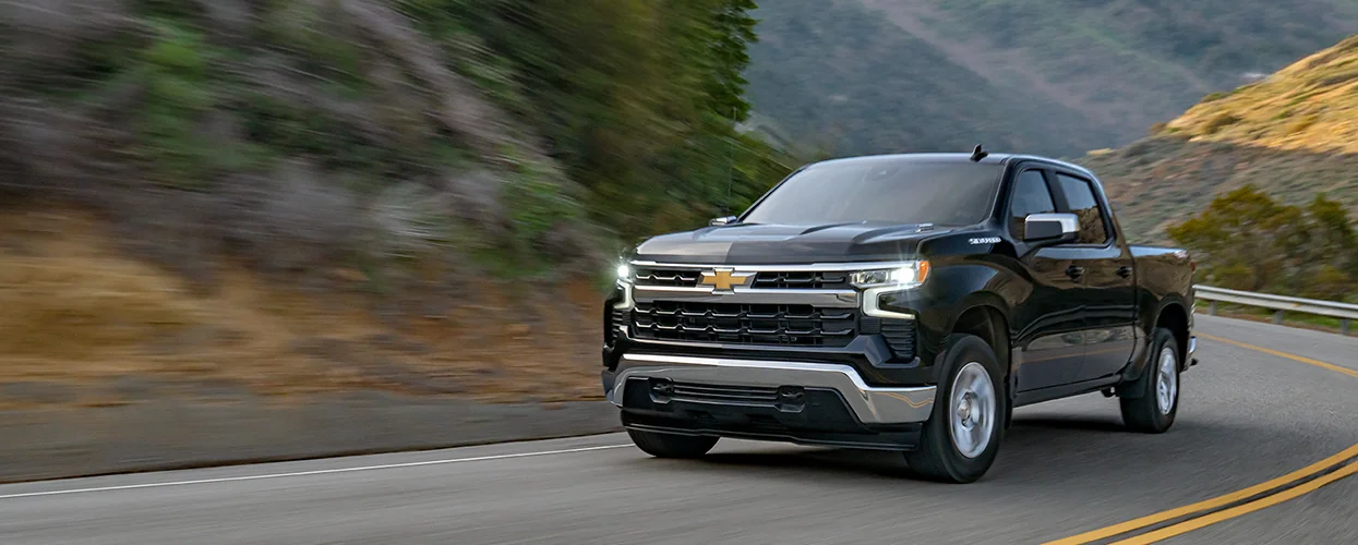 Front view of a black Chevrolet Silverado 1500 driving on a  road though some mountains