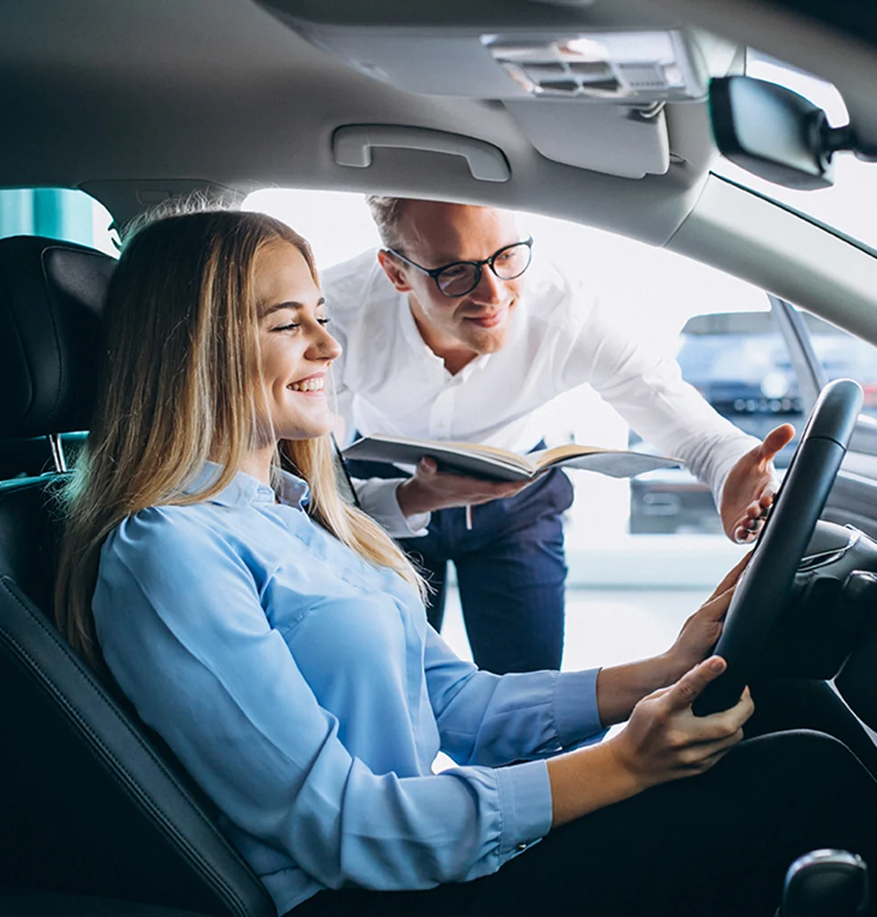 Sales person showing women the inside of a new car