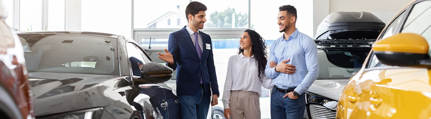 Car salesman showing a Kia to customers