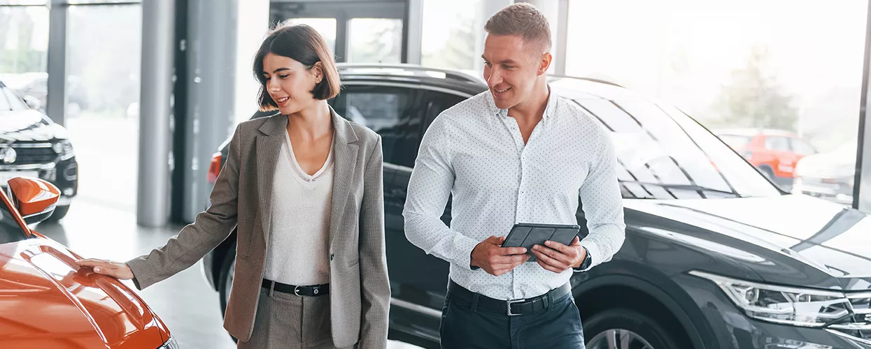 Car salesman showing a woman a new vehicle in a car dealership