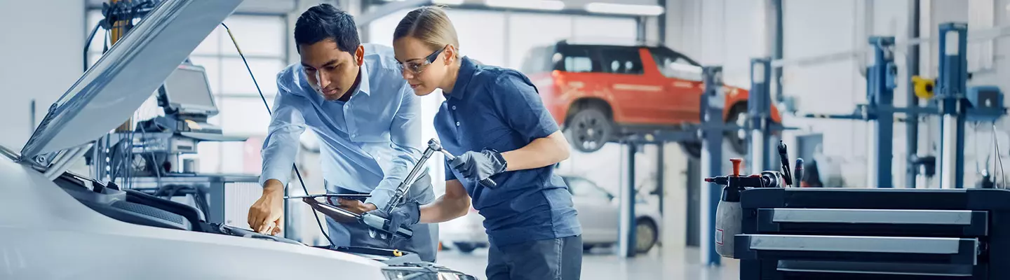 Mechanic and Tech working under the hood of a vehicle