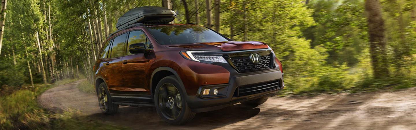 2021 Honda Ridgeline driving on dirt road with luggage in carrier on top