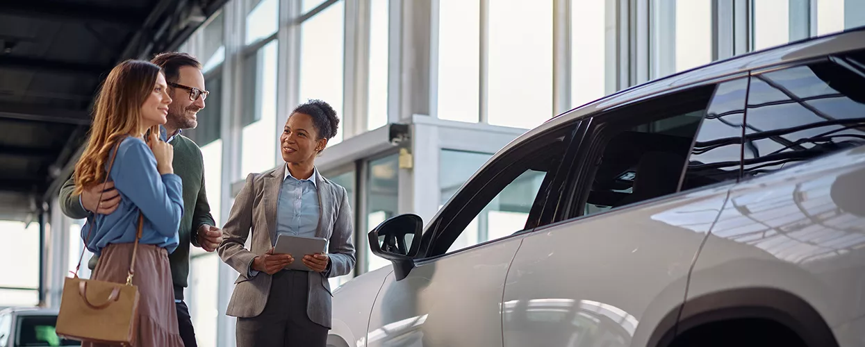 Car saleswoman showing a couple a new car in a car dealership