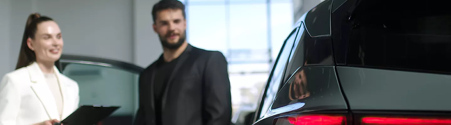 Saleswoman talking with a man about the vehicle they are looking at