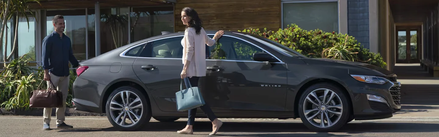 parked 2025 Chevrolet Malibu with couple departing