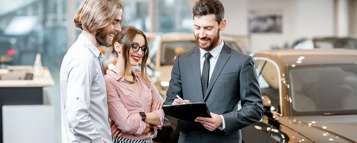couple speaking with car salesperson in the dealership showroom