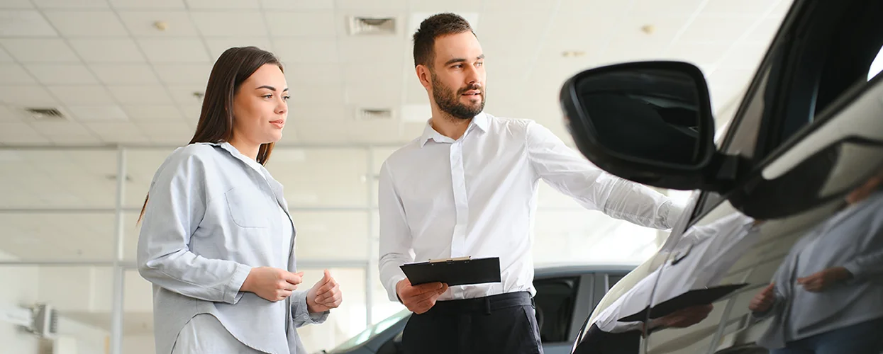 Sales person showing a customer a new car