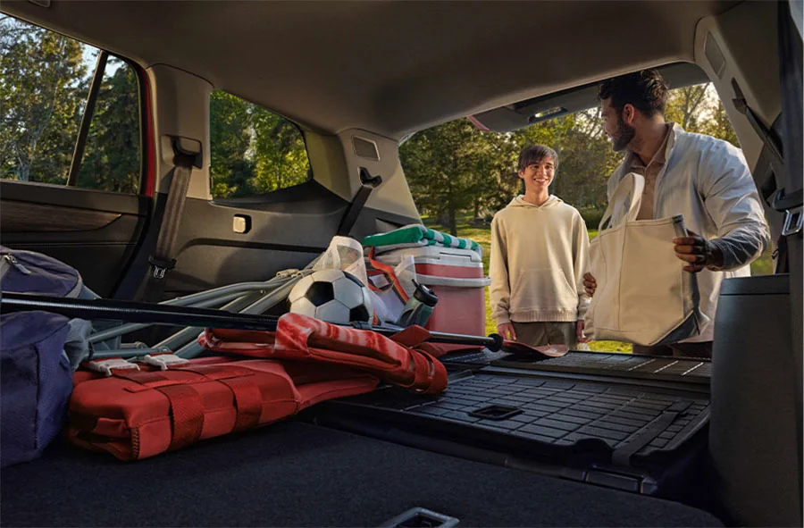 father and son unpacking suv with bags and other outdoor gear