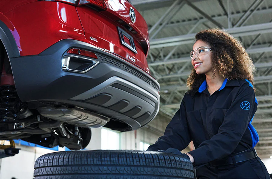 female mechanic moving a tire with the vehile raised in the lift