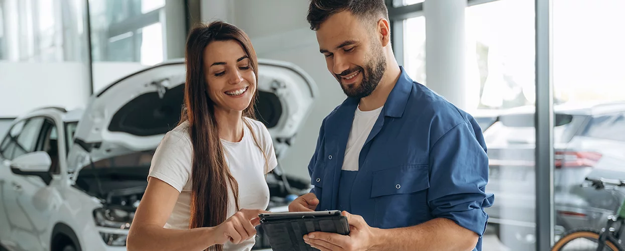 Blog Post in Customer reviewing vehicle maintenance information with an automotive service advisor inside a modern car service center