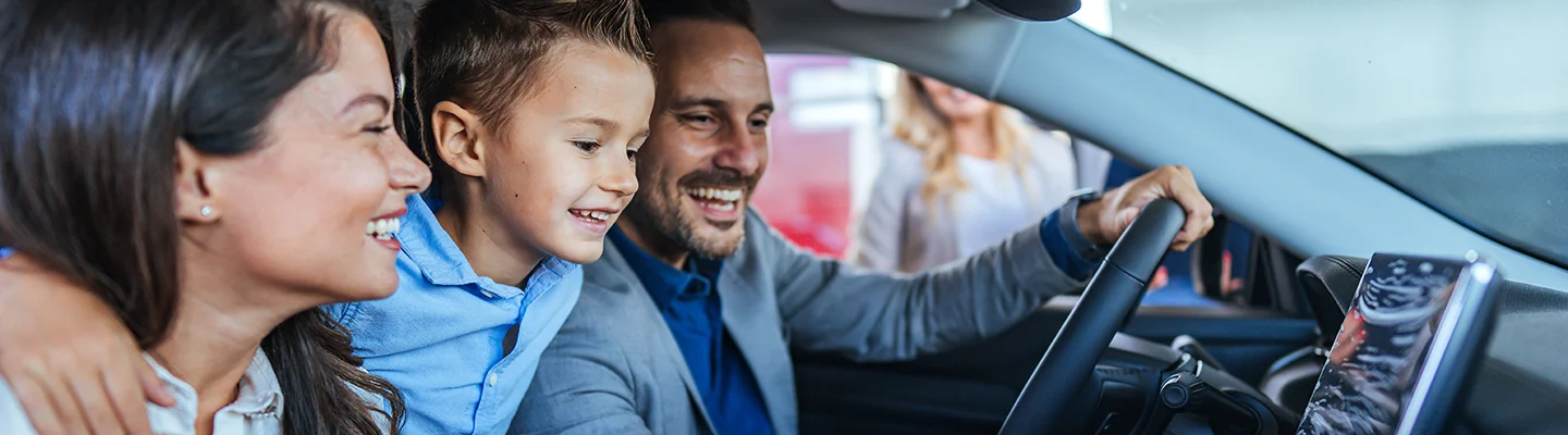 family of three smiling inside their new car