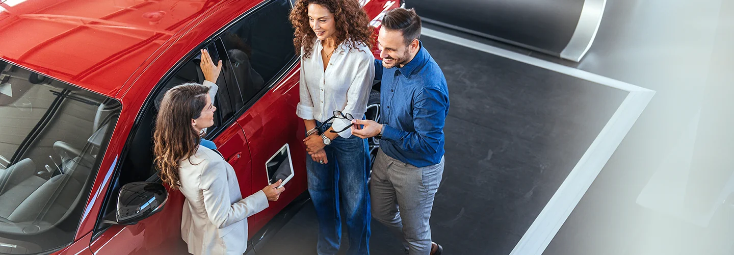 Sales person explaining information about a car to customers