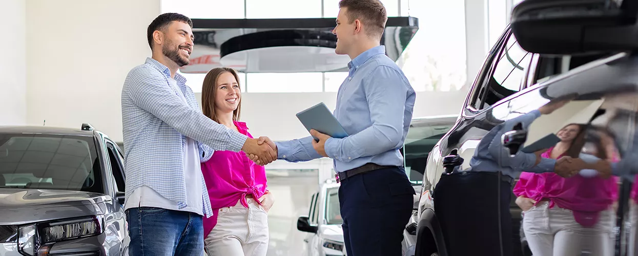 couple speaking with car salesman in showroom