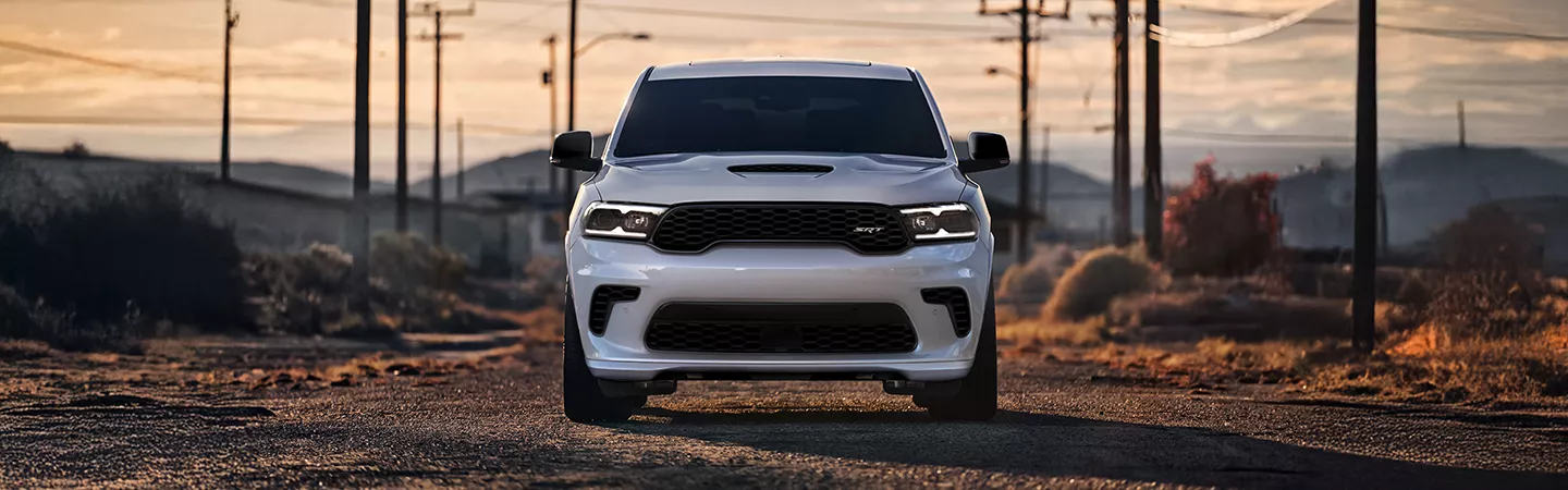 Front view of a 2025 Dodge Durango parked on a desert road with power lines in the background