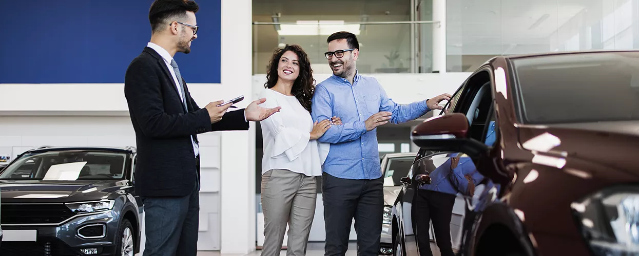 Car salesman showing a couple a new vehicle
