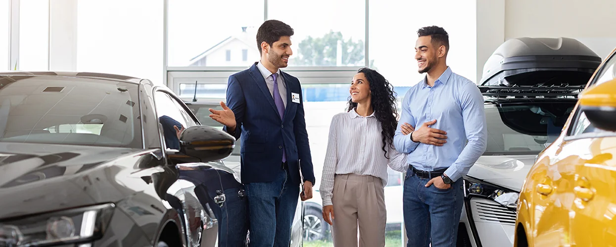 Sales person showing customers a new car