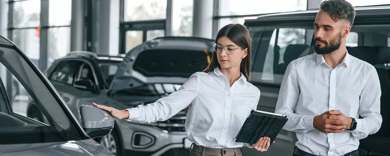 Two sales people looking over new pre-owned Vehicle