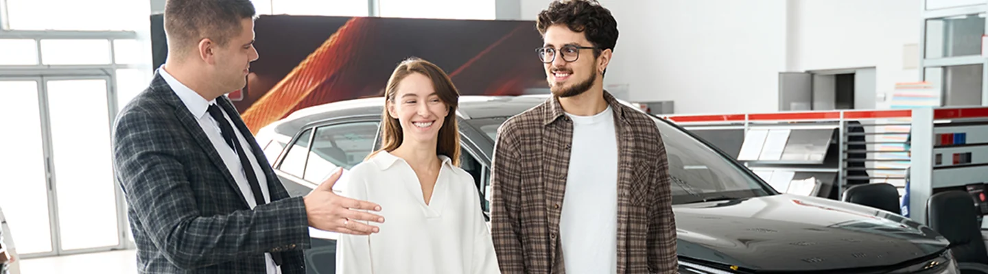 a couple speaks with salesperson in showroom discussng a great lease deal being offered