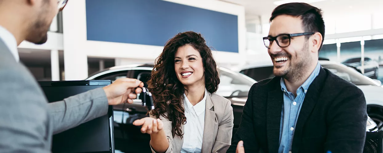 Car salesman handing keys to a new car owner