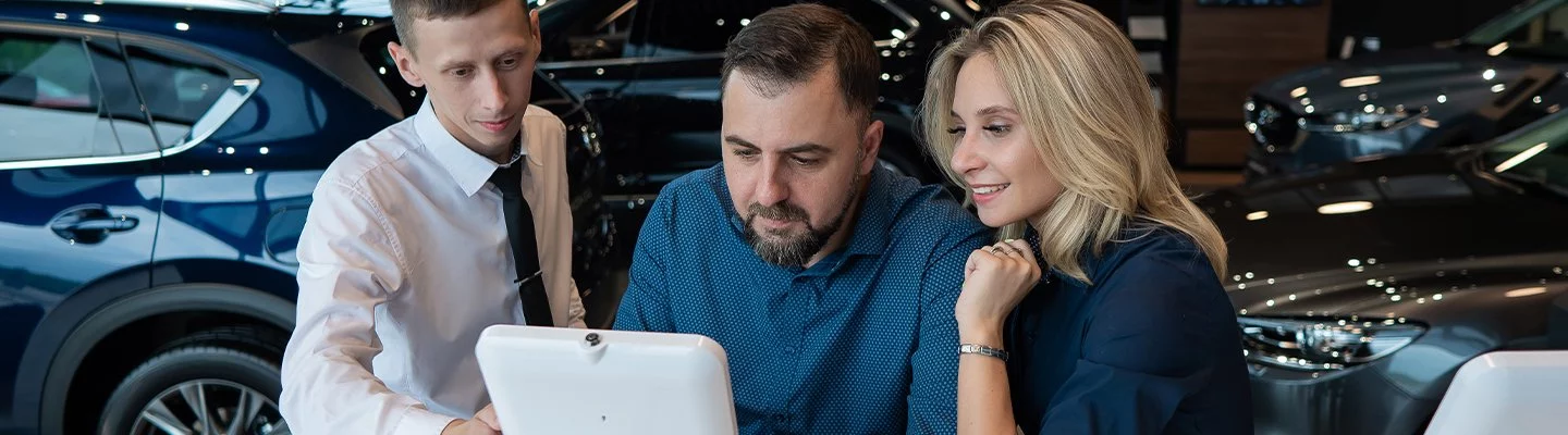 husband and wife looking at tablet with salesman
