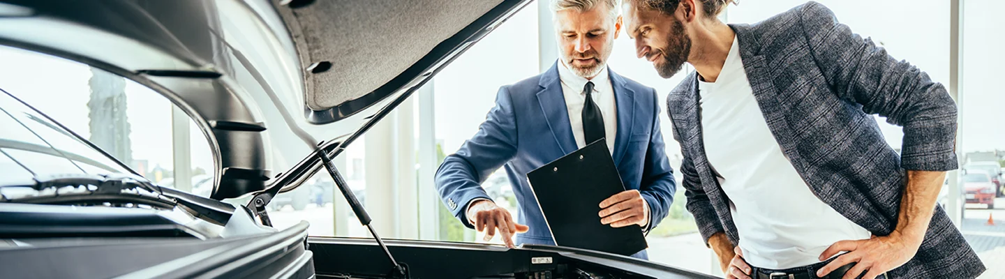 Sales person showing customer whats under the hood of a car