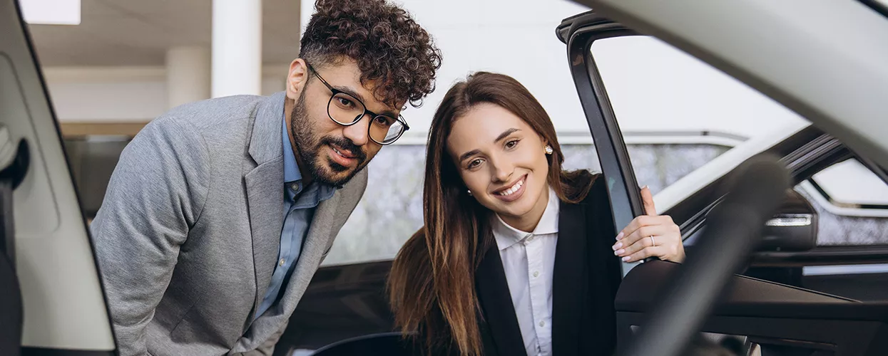 Two people looking at the interior of a new vehicle