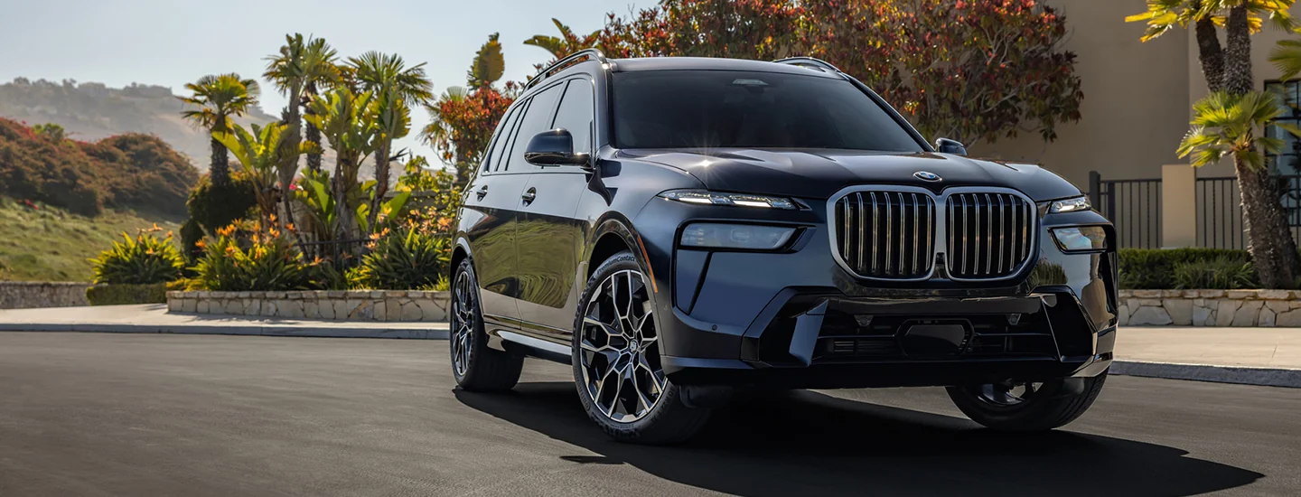 front view of a 2026 BMW X7 parked beside a beautiful home