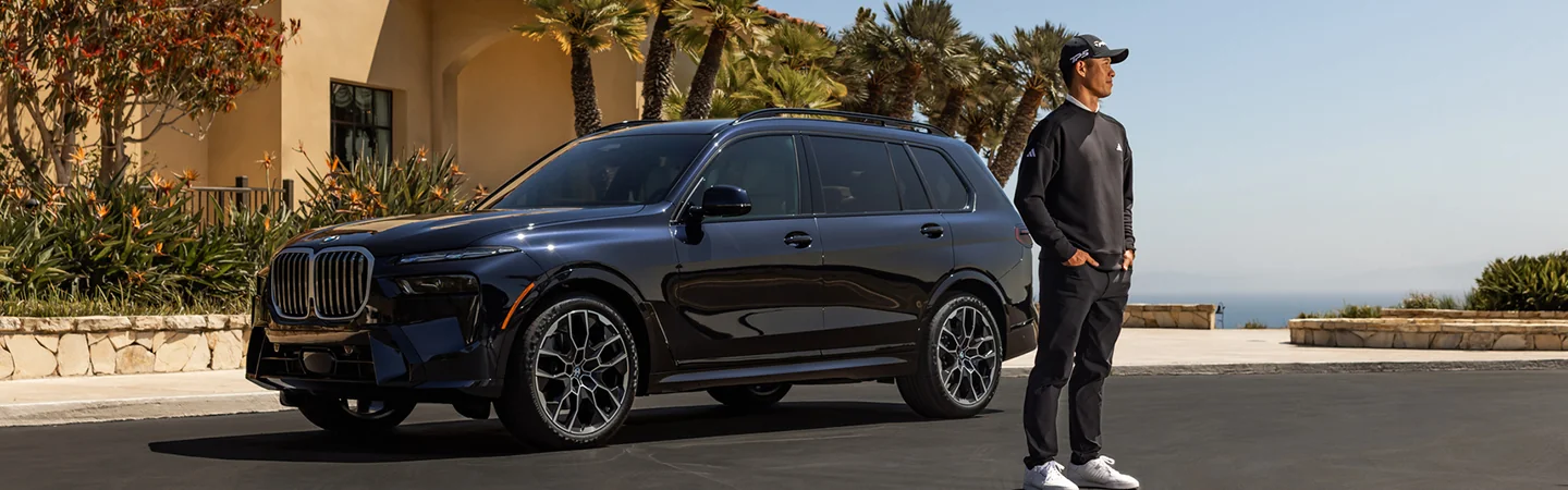 golfer standing beside a blue 2026 BMW X7 xDrive40i
