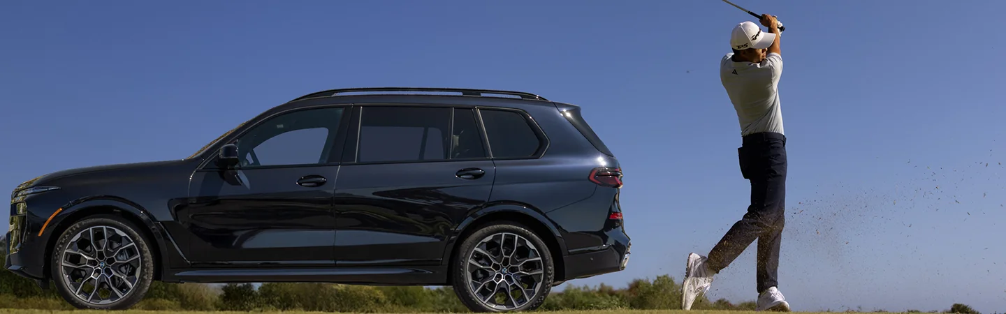 golfing in backswing stance beside a dark blue 2026 BMW X7 xDrive40i