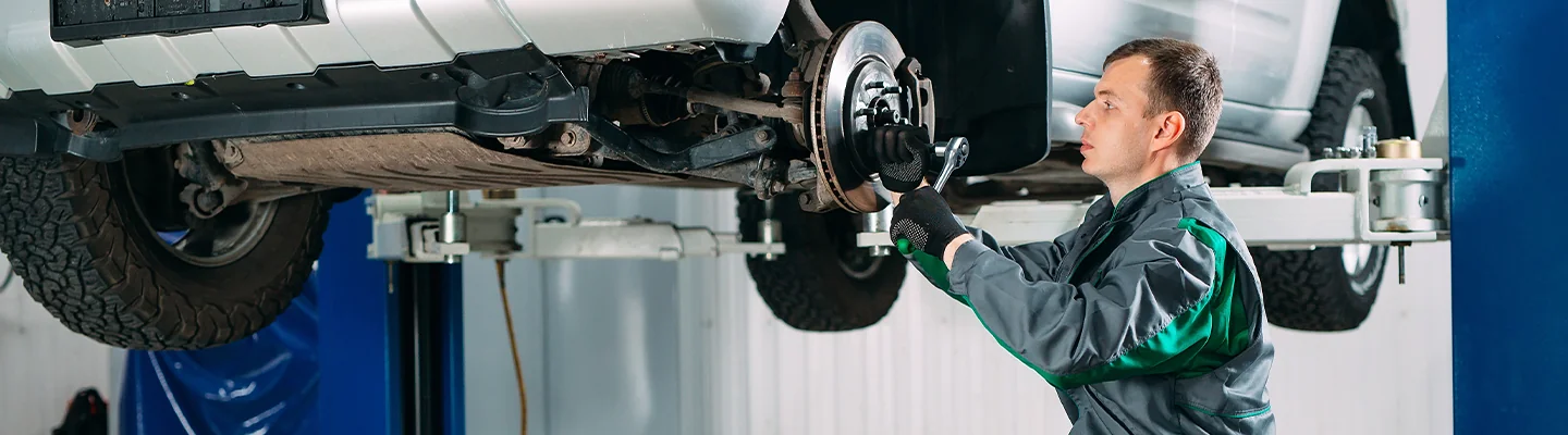 mechanic working on brakes with the vehicle on the lift