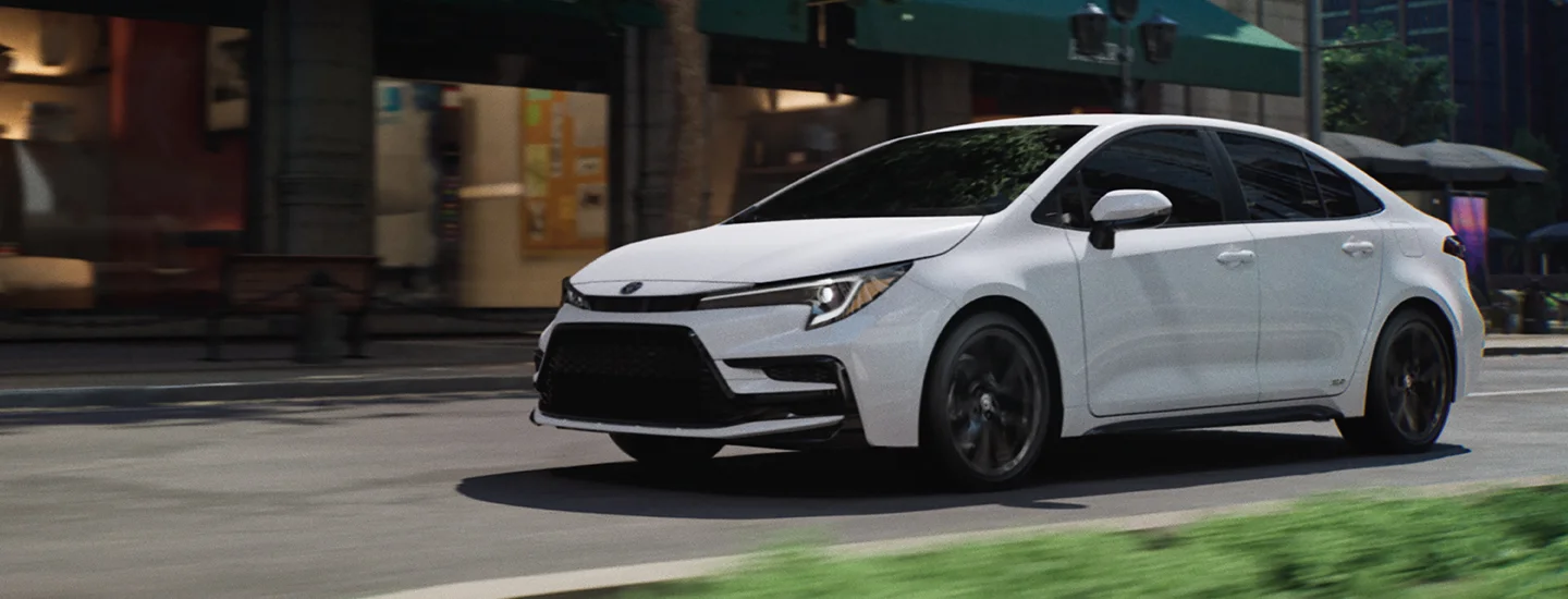 white 2025 Toyota Corolla driving past shops