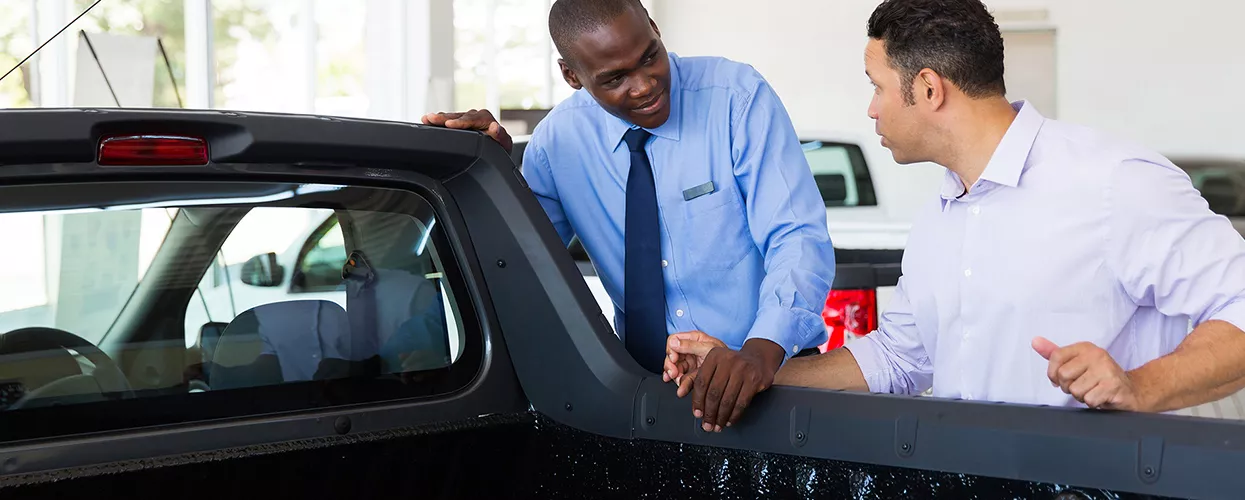 Car salesman showing a customer a truck at a car dealership