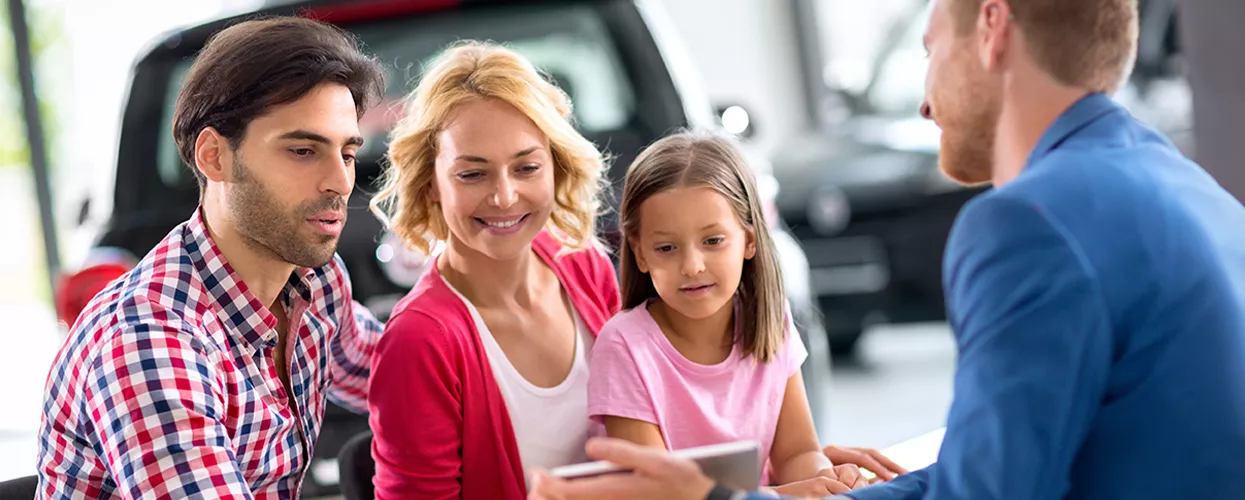 Family looking at a tablet in a car dealership
