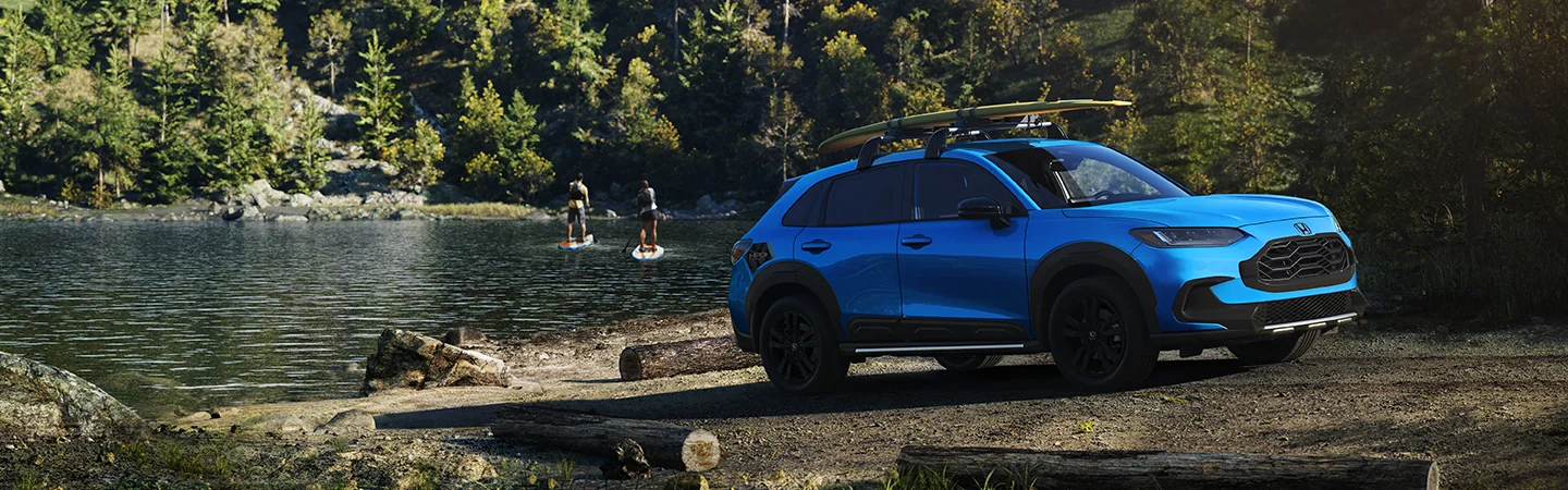 A blue 2026 Honda HR-V parked a lake with people paddle boarding on it