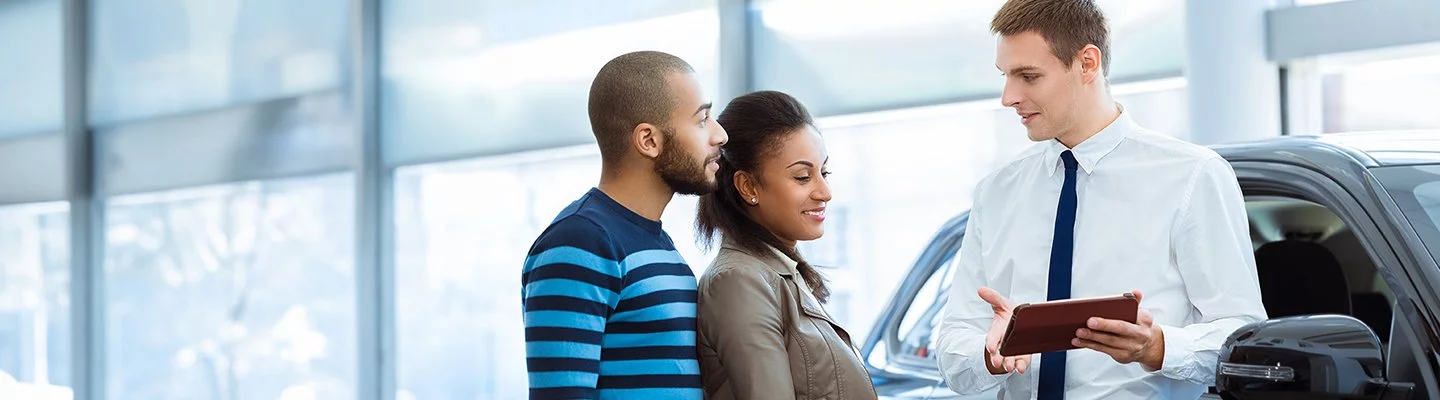 husband and wife looking at tablet talking with a salesman