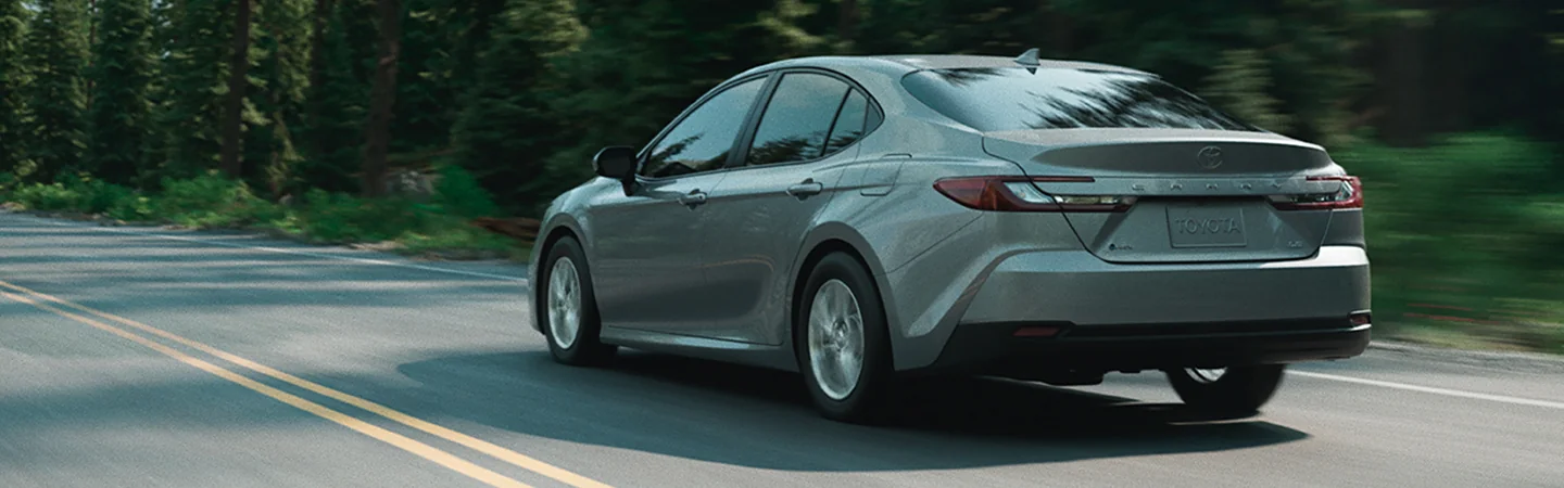 Rear view of 2025 Toyota Camry driving down a road