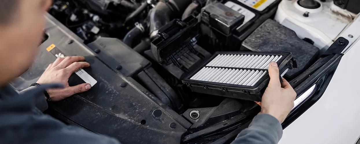 Service mechanic looking at a car's air filter