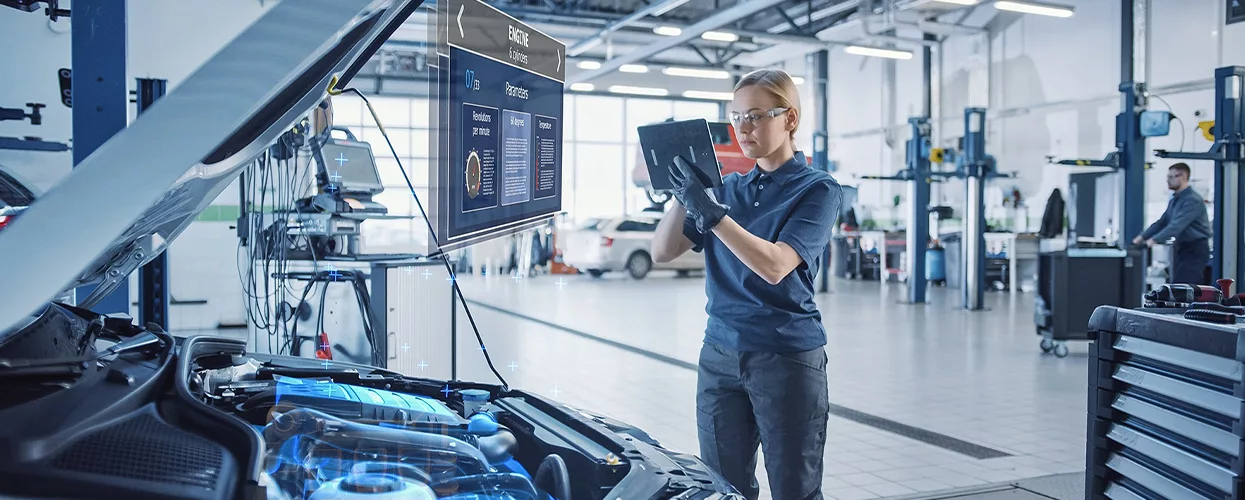 Automotive technician using advanced diagnostic software and a digital tablet to inspect a vehicle in a modern service center